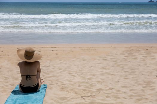 Beautiful woman with bikini enjoying summer holiday the Beach and sun sitting in sand looking happy. with copy space for text or design. Asian Thailand