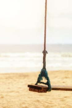 Summer concept. Wood swing hanging from coconut palm tree over beach sea. Asia Thailand. with copy space for text or design