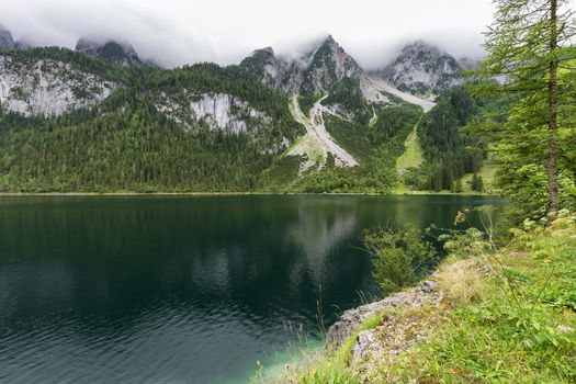 Great azure alpine lake Vorderer Gosausee. Picturesque and gorgeous rain clouds