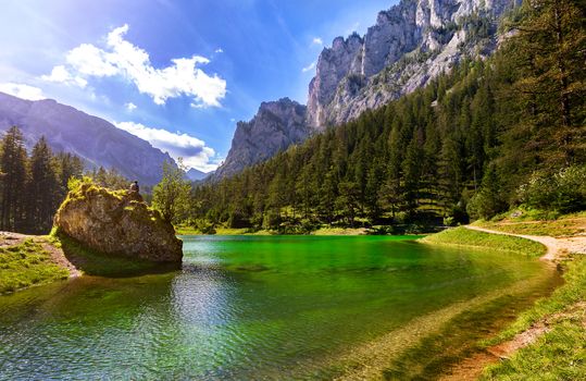 Man sitting on rock and relaxing in nature at green beautiful lake