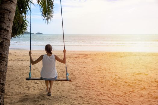 woman traveler sitting on the swing relex on the beach. women tourist enjoy with view of the sea on holiday time. Asia Thailand. With copy space for text or design