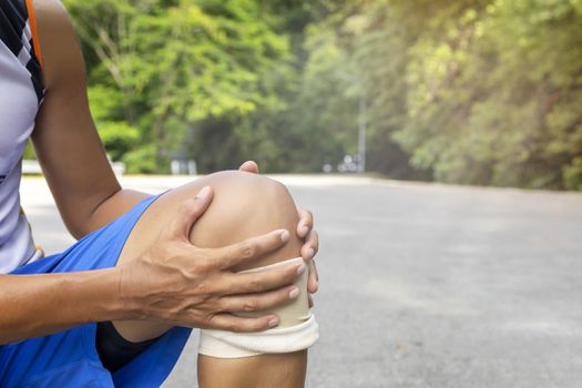 Man with blue runing shorts use hands hold on his knee after running on road in morning time with copy space for text or design