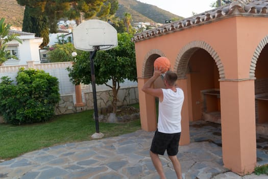 Young man plays basketball throws a ball into a basket in a jump