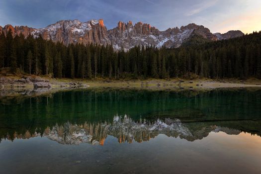 Sunset at Carezza lake with beautiful reflections of dolomites mountains