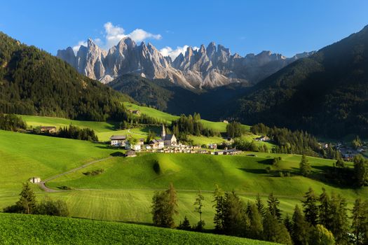 Santa Magdalena village in Val di Funes on the italian Dolomites. Autumnal view of the valley with colorful trees and Odle mountain group on the background in the evening at sunset. Italy.