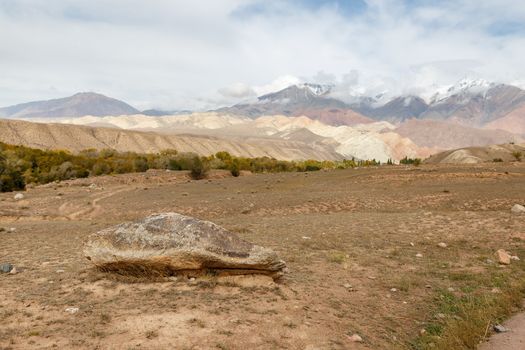 a large stone lies on the ground, beautiful mountains, Kyrgyzstan