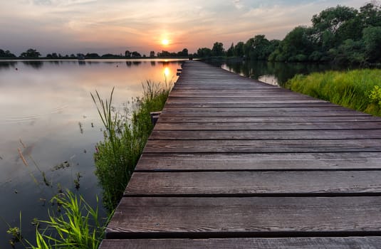 Wooden path over the lake at sunset