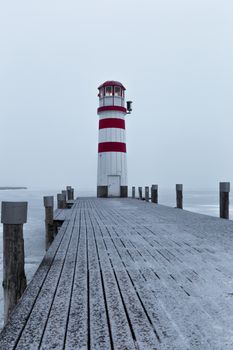 Lighthouse at sunrise with fog and rain during winter
