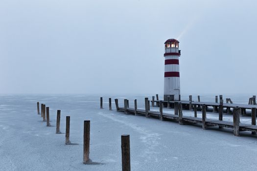 Lighthouse at sunrise with fog and rain during winter