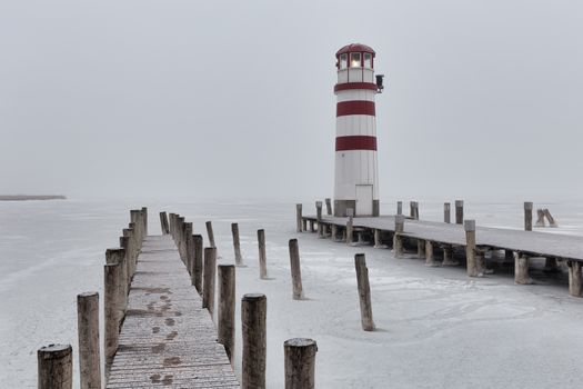 Lighthouse at sunrise with fog and rain during winter