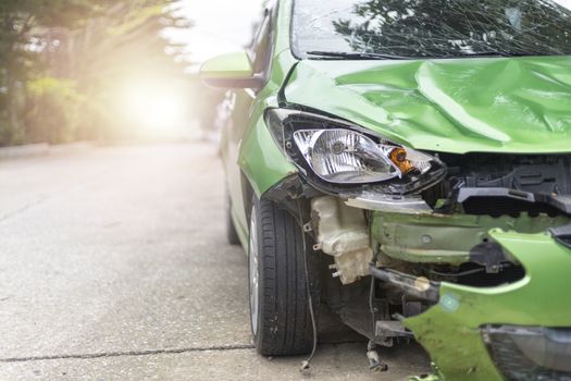 Front of green color car damaged and broken by accident on road parking can not dirve any more