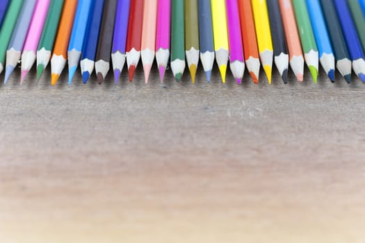 Many color pencils on wood background with copy space for text or design.
