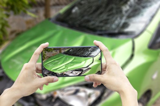 2 hand of woman hold smartphone for take photo of front green color car accident 