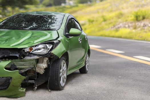 Front of green color car damaged and broken by accident on road parking can not dirve any more