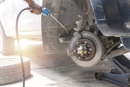 Mechanic use air gun clean disc break take dust removes before change break pat.