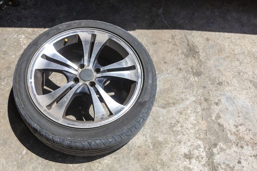 One car wheel with tyre on ground. With copy space for text or design.