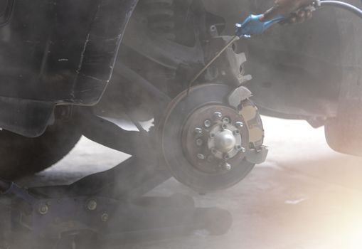 Mechanic use air gun clean disc break take dust removes before change break pat.