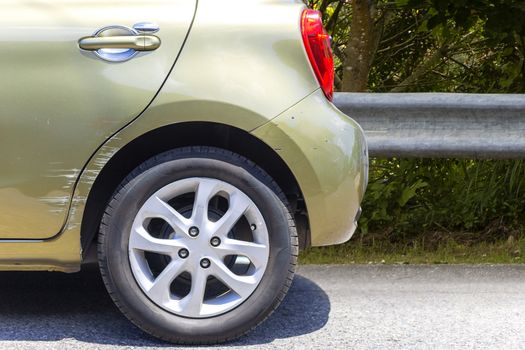 Car crash. Beside the deep green color car have scratch from damage on road. Close up scratch