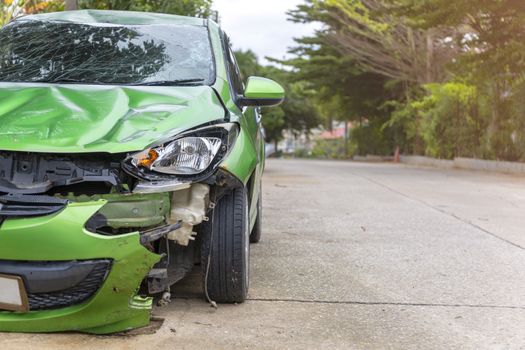 Front of green color car damaged and broken by accident on road parking can not dirve any more