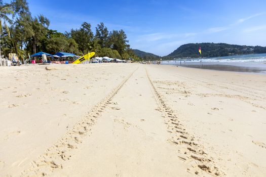 Summer concept. Sand on the beach with clear sky moutain and people play water sea.