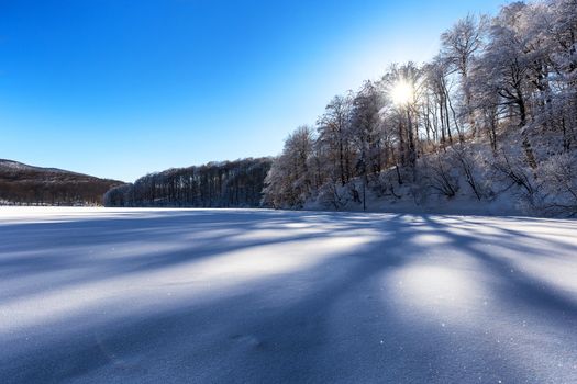 Frozen lake covered wth snow on a sunny day