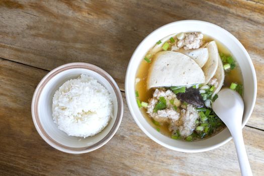 Top view Soup with pock, pock stick, mushroom, vegetable in white bowl near have rice in small bowl on wood table. with copy space for text or design
