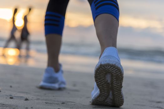 Woman running on the beach at sunrise closeup on shoe. Patong beach, Phuket, Thailand