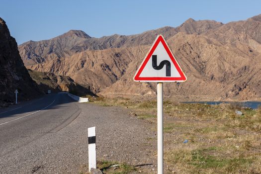 sign winding road on a mountain road, warning traffic sign kyrgyzstan.