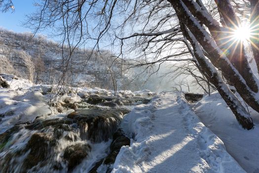 Winter path covered by snow and river flowing thru plitvice lake, Croatia