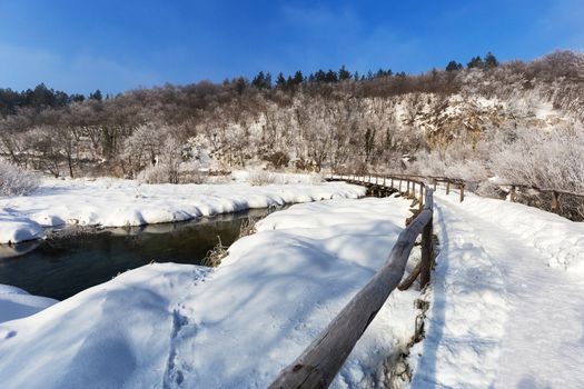 Winter path covered by snow thru plitvice lake, Croatia