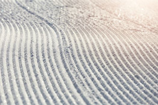 Close-up ski piste, ski slope, Abstract background with tracks on the snow, newly groomed snow