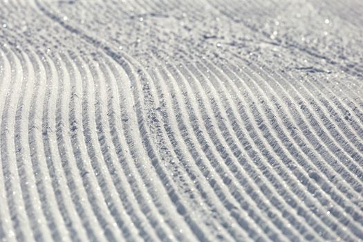 Close-up ski piste, ski slope, Abstract background with tracks on the snow, newly groomed snow