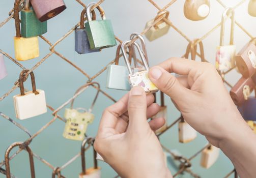 Women hand holding master key  with bridge rail locks of love