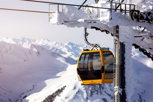 Gondola lift. Cabin of ski-lift in the ski resort in the early morning at dawn with mountain peak in the distance. Winter snowboard and skiing concept 