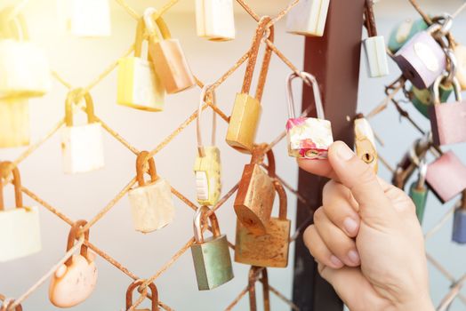 Women hand holding master key  with bridge rail locks of love
