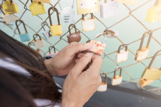 Women hand holding master key  with bridge rail locks of love