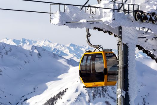 Gondola lift. Cabin of ski-lift in the ski resort in the early morning at dawn with mountain peak in the distance. Winter snowboard and skiing concept 