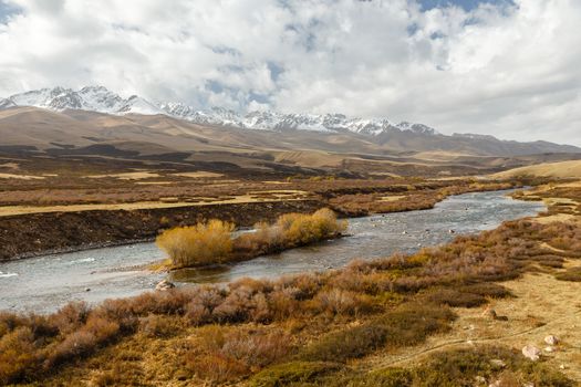 Susamyr river in Kyrgyzstan, river flows along the snowy mountains