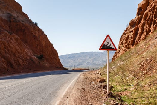 Downhill road sign with percentage on a mountain road, warning traffic sign kyrgyzstan