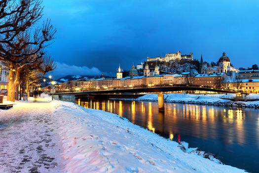 Classic view of the historic city of Salzburg with Salzburg Cathedral and famous Festung Hohensalzburg illuminated in winter, Salzburger Land, Austria