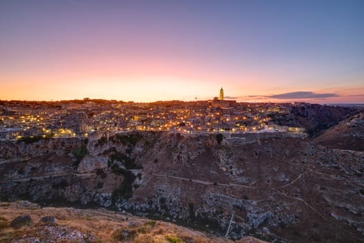 The beautiful old town of Matera and the canyon of the Gravina river after sunset