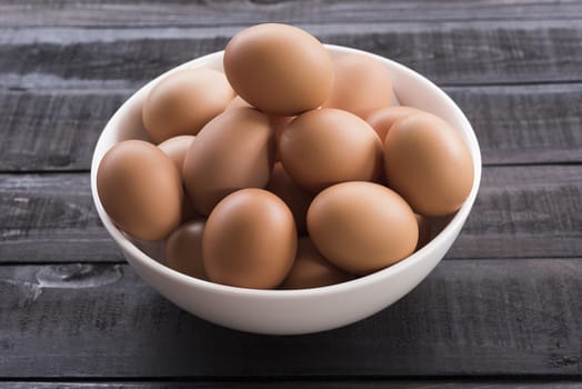 Chicken egg in white bowl on Black color wood table
