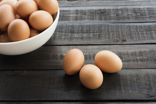 Fresh hen egg in white bowl and 3 hen egg out side on Black color wood table