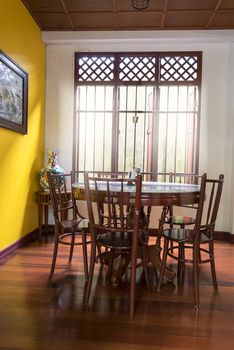 Wooden round table and chair chiness style near window have ray of light on wood floor and yellow wall have lotus chiness picture