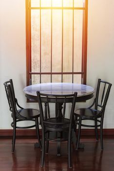Wooden round table and chair chiness style near window have ray of light on wood floor and white wall 