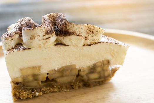 Banoffee pie with chocolate powder on wooden plate 