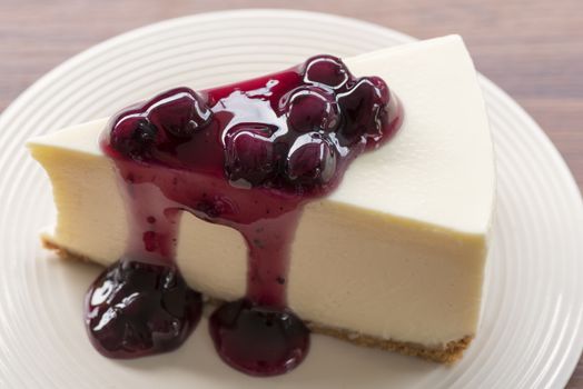 Blueberry cream cheesecake in white plate on wood table