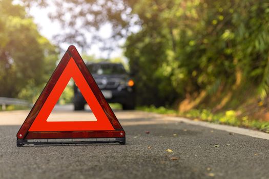 Red triangle, red emergency stop sign, red emergency symbol and black car stop and park on road.