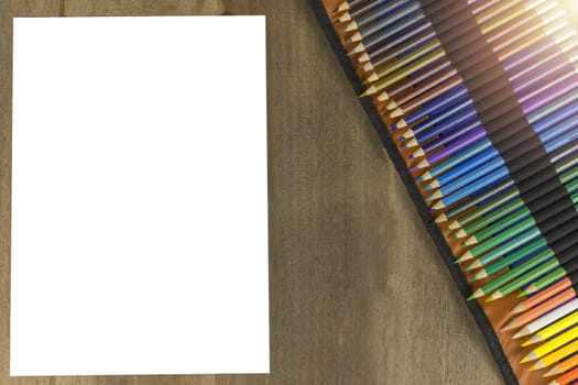 Many pencil colors with blank white paper on wood table. With copy space for text or design.