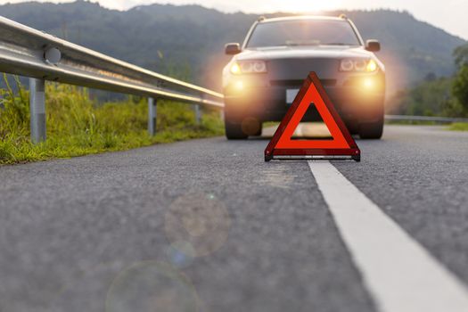 Red triangle, red emergency stop sign, red emergency symbol and black car stop and park on road.